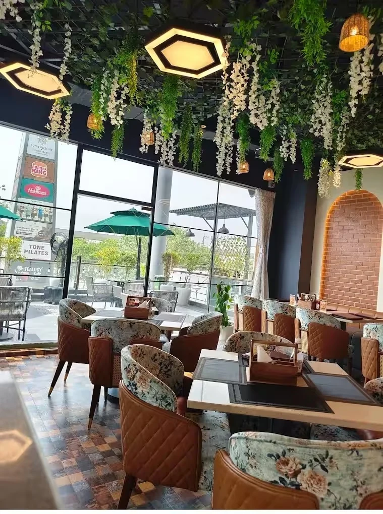 Floral dining chairs beneath greenery in the sunlit café